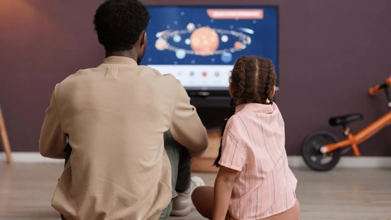Father and daughter viewing television together.